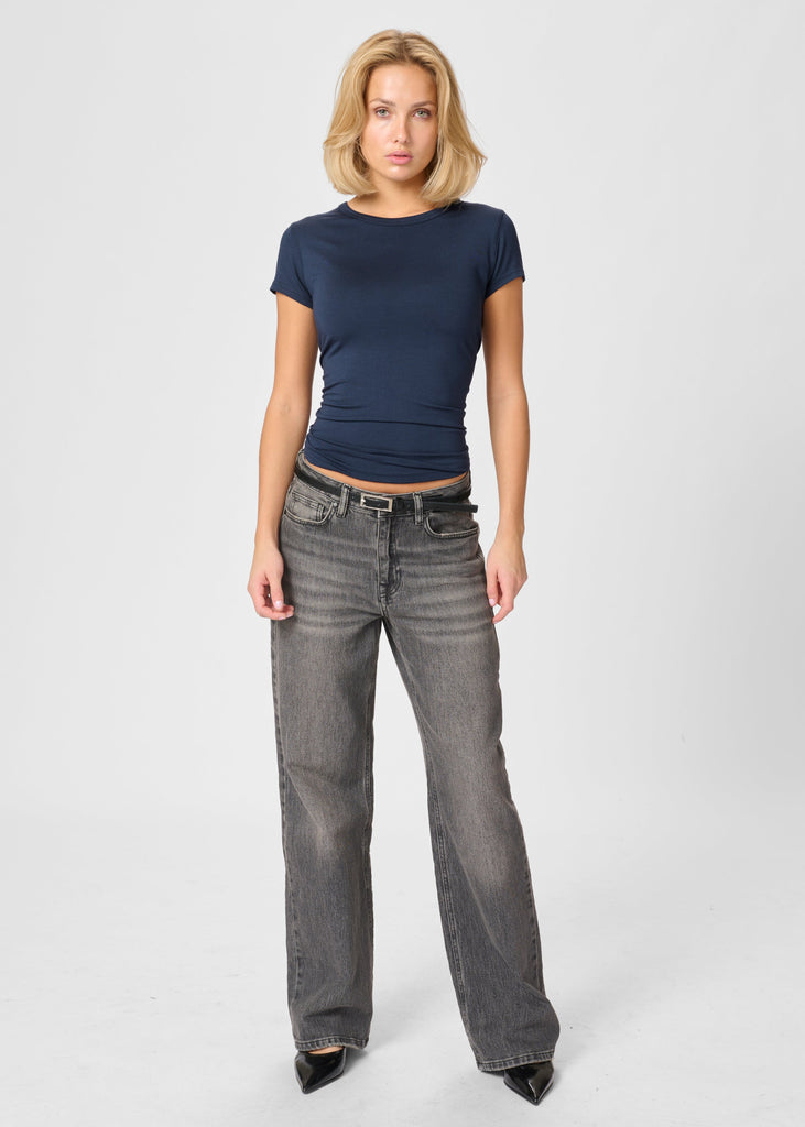 Woman wearing a navy blue t-shirt and gray jeans on a white background