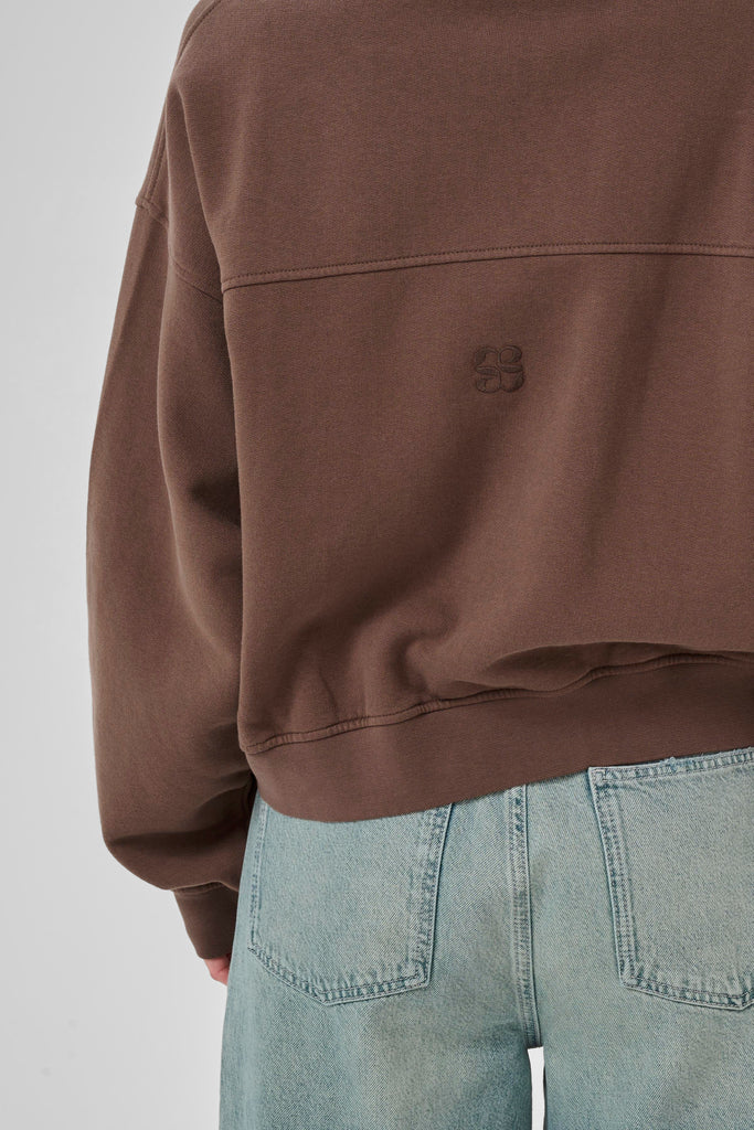 Brown jacket and light blue jeans on a plain background