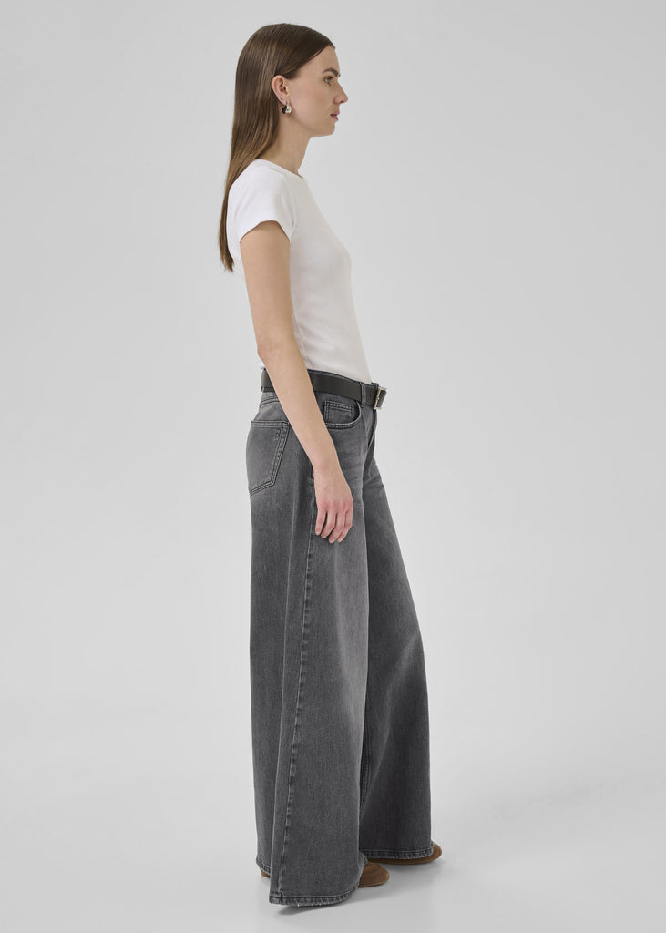 Woman wearing a white t-shirt and gray wide-leg jeans on a white background