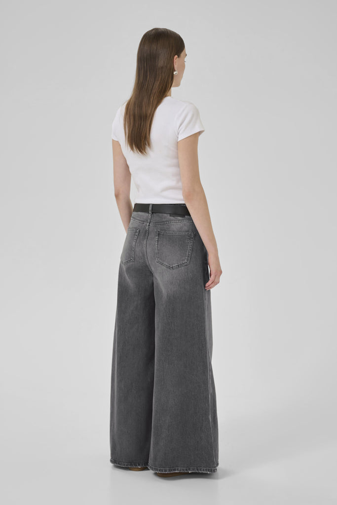 Person wearing a white t-shirt and gray wide-leg jeans on a plain background