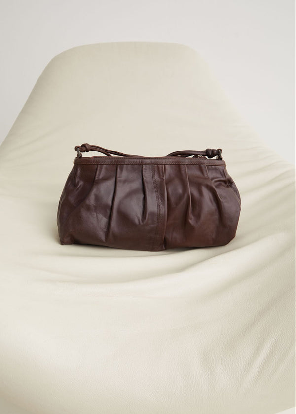 Brown leather handbag on a beige cushion
