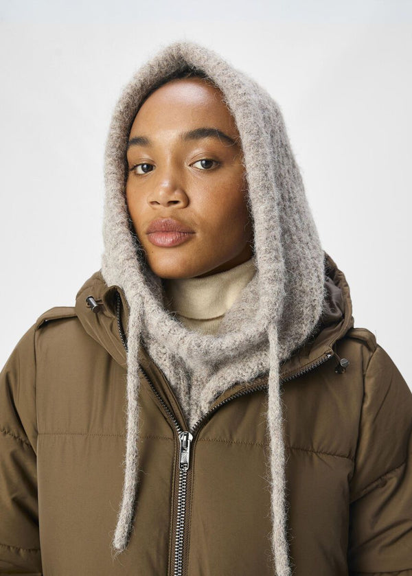 Person wearing a brown jacket with a fur-lined hood against a white background