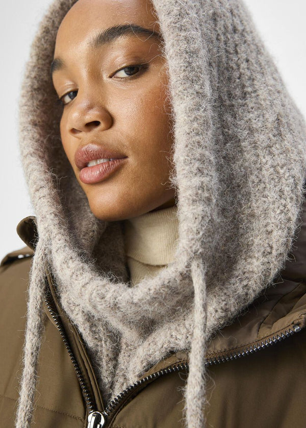 Person wearing a brown coat with a fur-lined hood against a white background