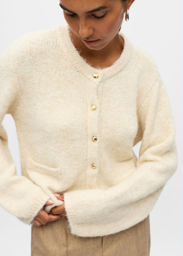 Person wearing a cream cardigan on a plain background