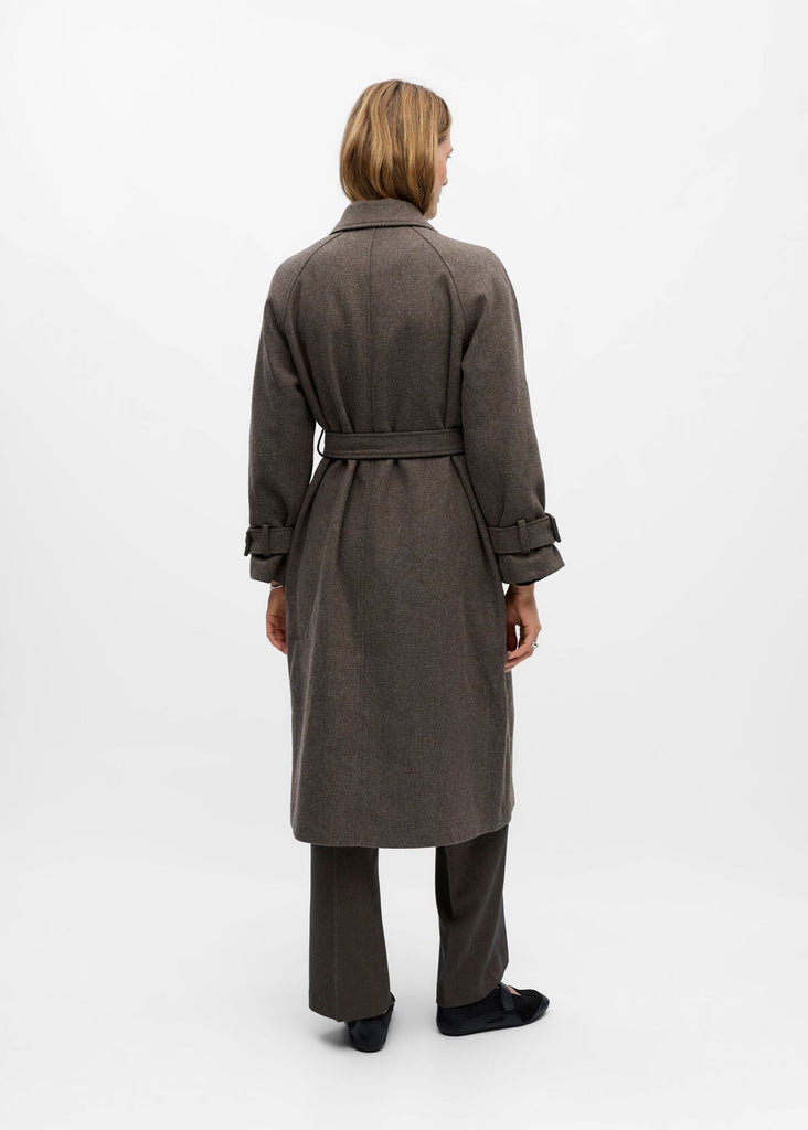 Person wearing a long dark coat on a white background