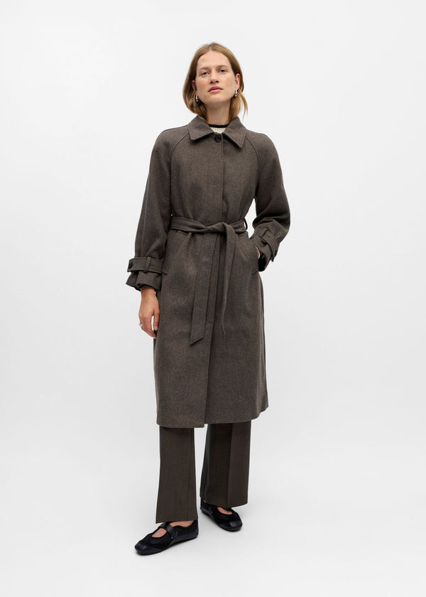 Woman wearing a long brown coat on a white background