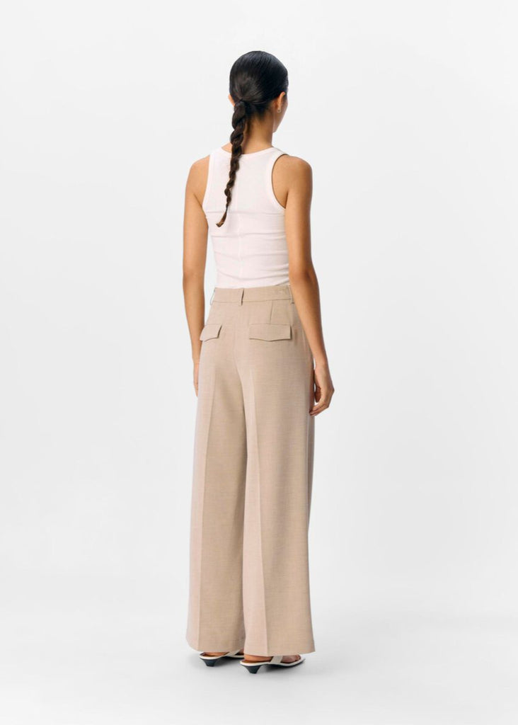 Woman wearing beige wide-leg pants and a white top on a white background
