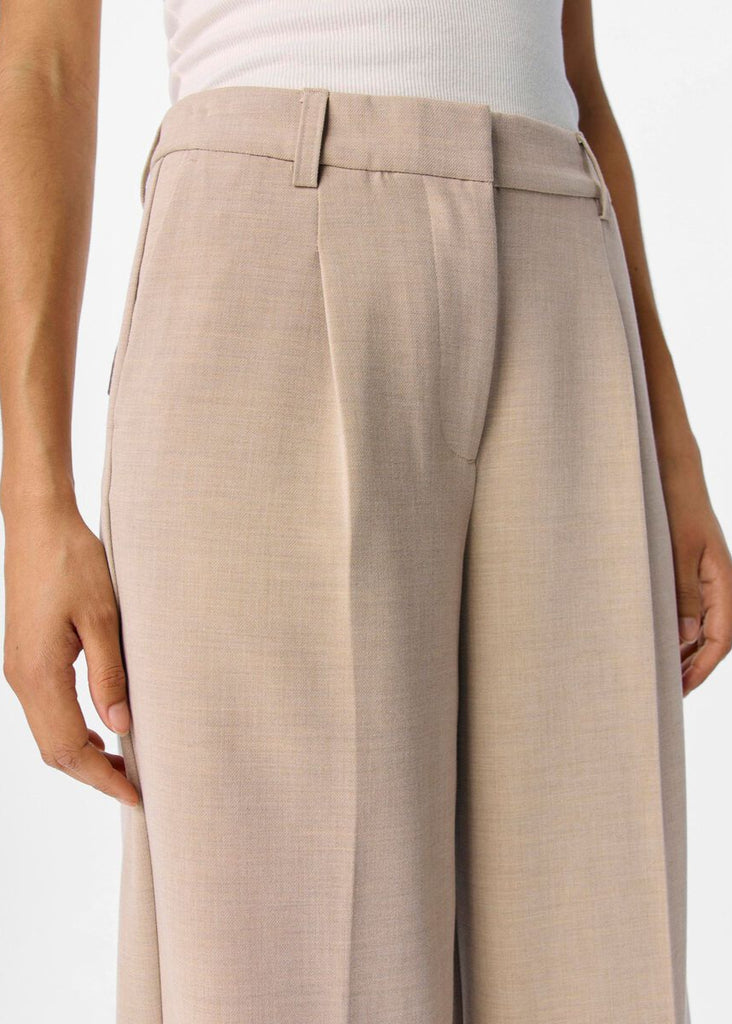Beige wide-leg pants worn by a person on a white background
