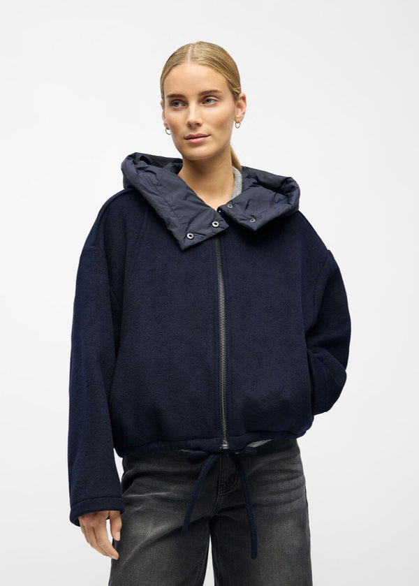 Person wearing a navy blue hoodie with a gray hood on a white background