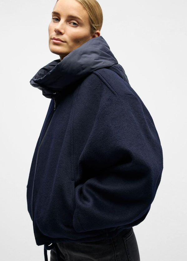 Person wearing a navy blue hoodie on a light gray background