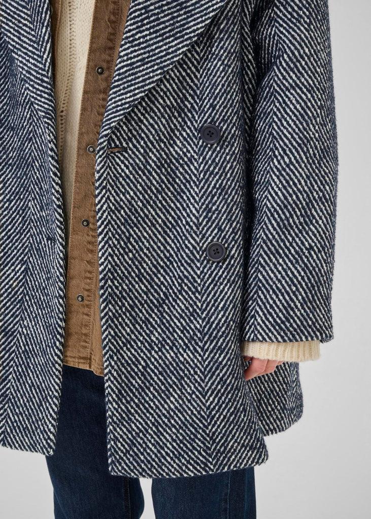 Herringbone patterned coat with a neutral-colored lining on a plain background
