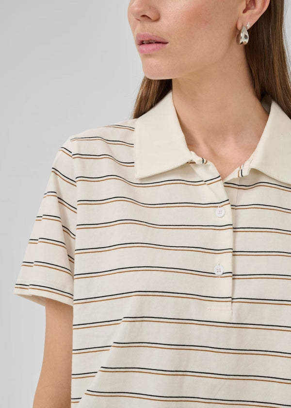 Close-up of a person wearing a beige and brown striped polo shirt on a gray background
