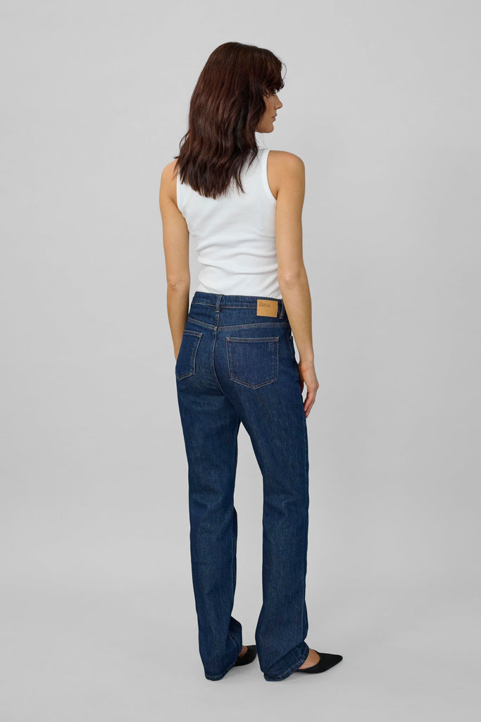 Woman wearing blue jeans and a white top on a gray background