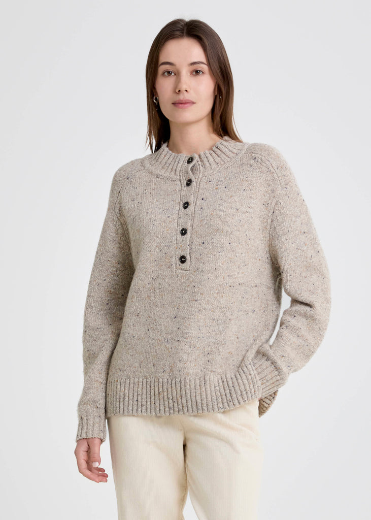 Woman wearing a beige knitted sweater with buttons on a white background