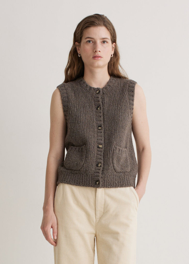 Woman wearing a brown knitted vest on a plain background