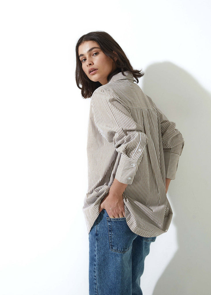 Person wearing a striped shirt and jeans against a white background
