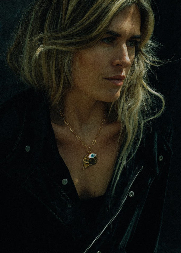 Woman wearing a necklace with a pendant against a dark background