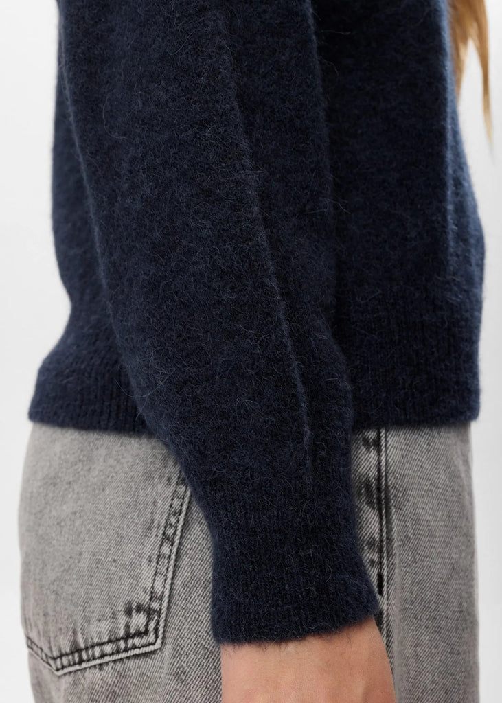 Navy sweater worn over gray pants on a white background