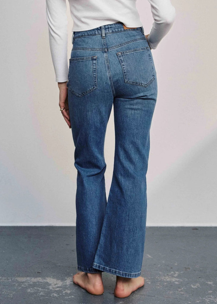 Person wearing blue jeans with a plain background
