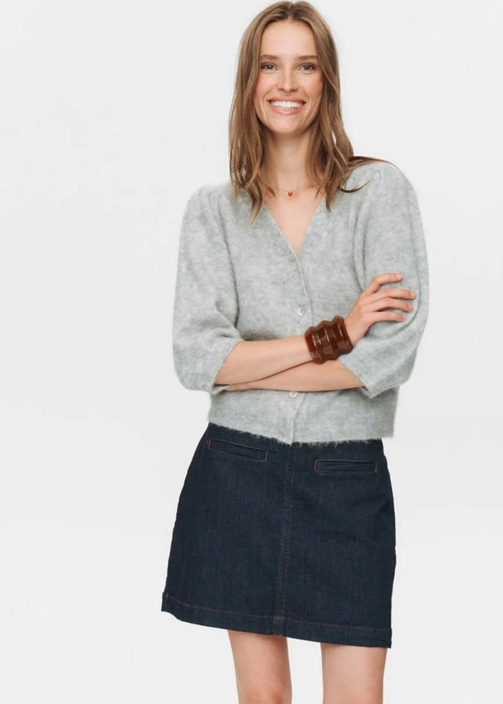 Woman wearing a gray sweater and black skirt on a white background