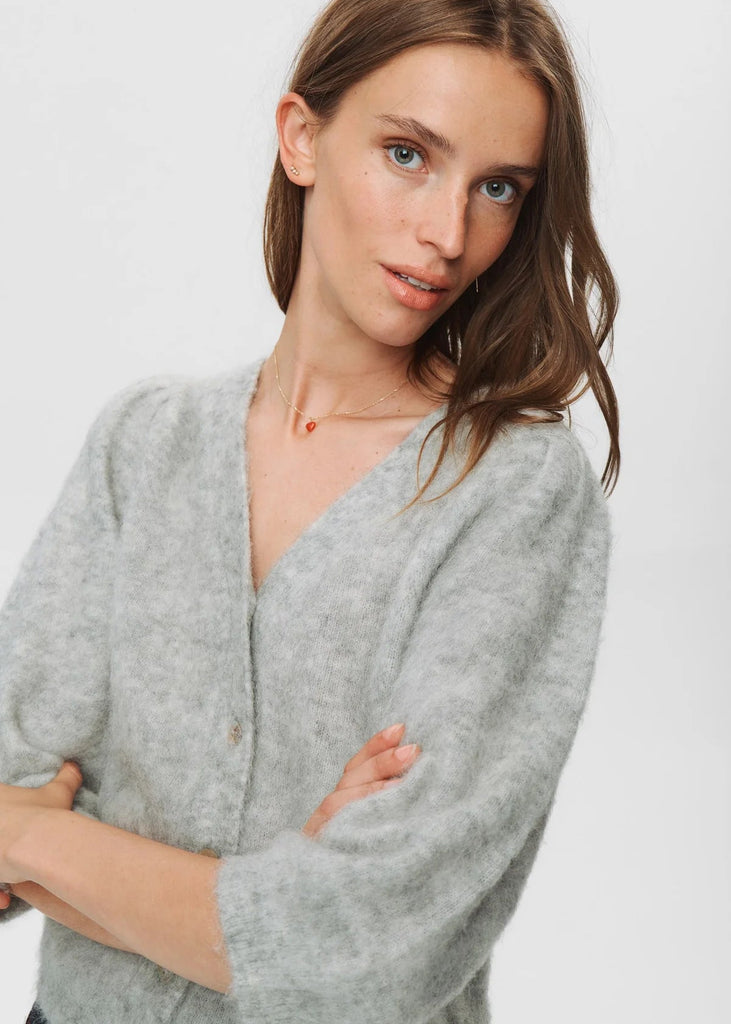 Woman wearing a gray sweater against a white background