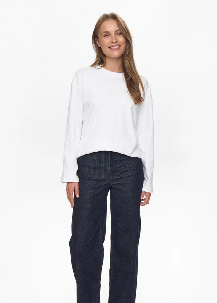 Woman wearing a white blouse and dark pants on a white background