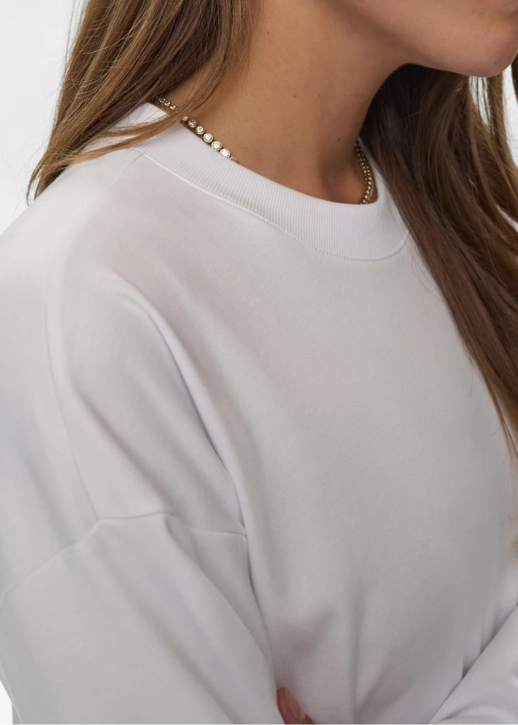 Close-up of a person wearing a light gray sweater with a blurred background