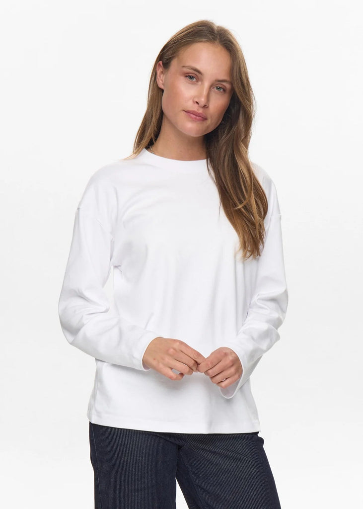 Woman wearing a white sweater and dark pants on a white background