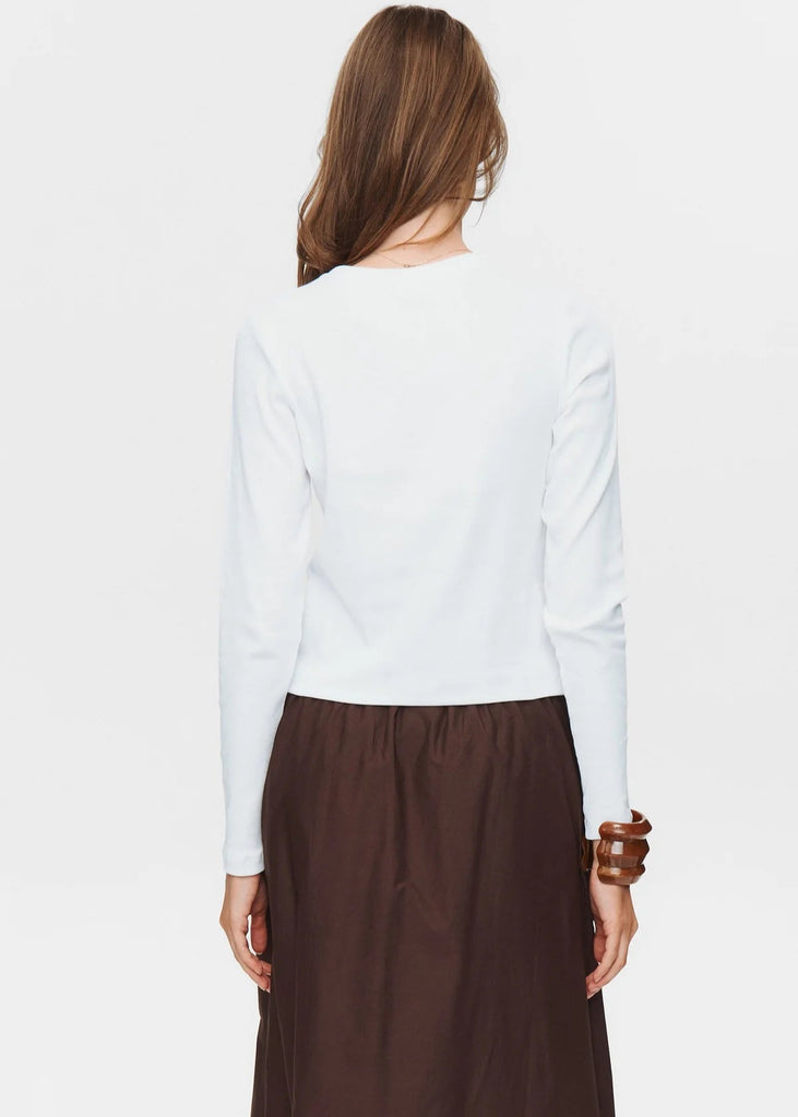 Person wearing a white long-sleeve top and brown skirt on a white background