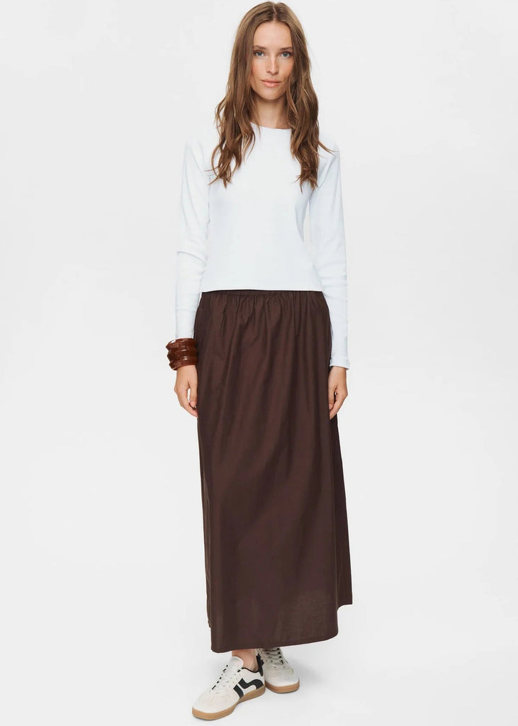 Woman wearing a white top and brown skirt on a white background