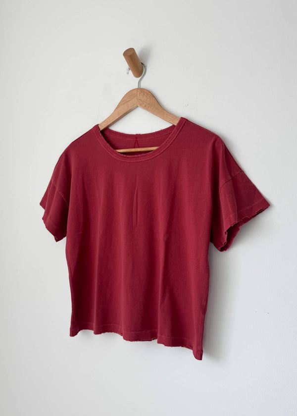 Red t-shirt on a wooden hanger against a white background