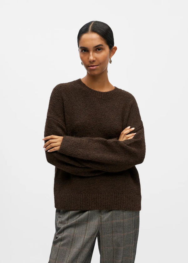 Woman wearing a brown sweater with arms crossed on a white background