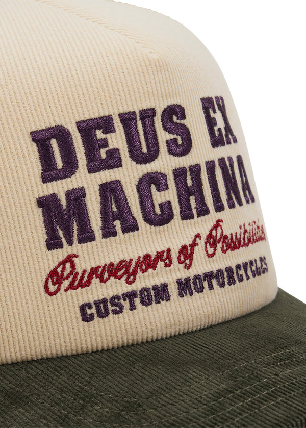 Cap with 'Deus Ex Machina' branding on a beige and green background