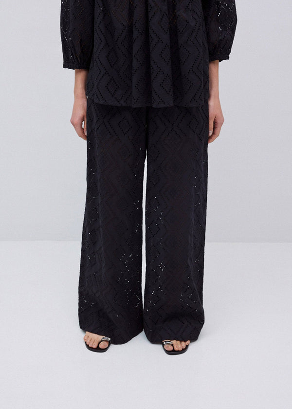 Person wearing a black quilted outfit with sequins on a white background