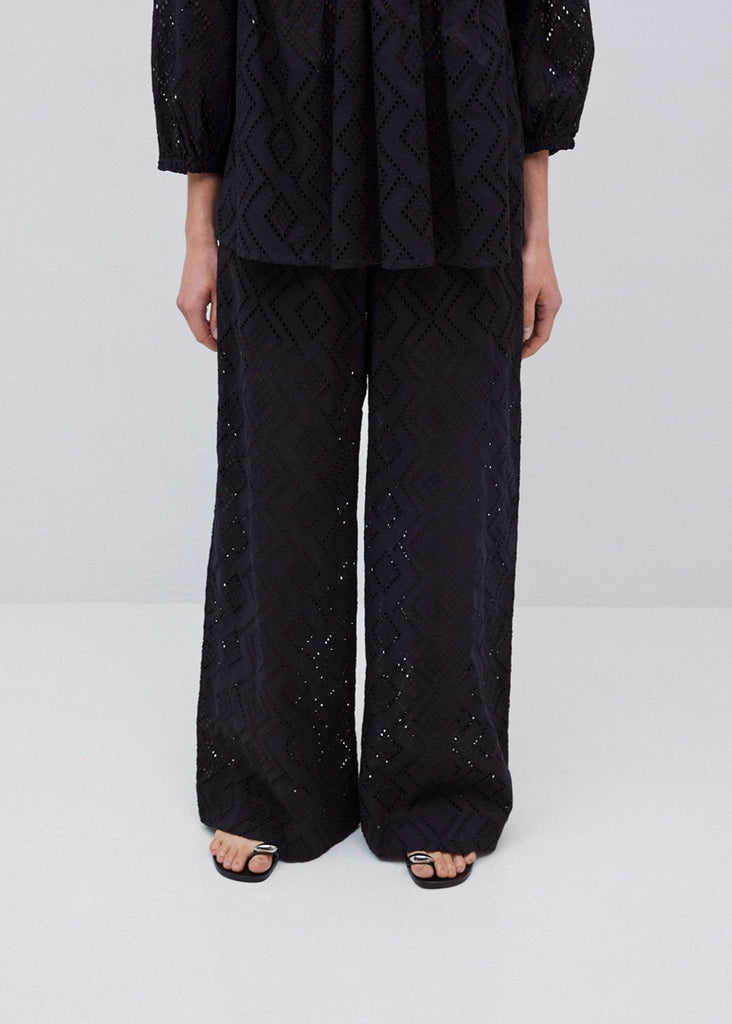 Person wearing a black quilted outfit with sequins on a white background