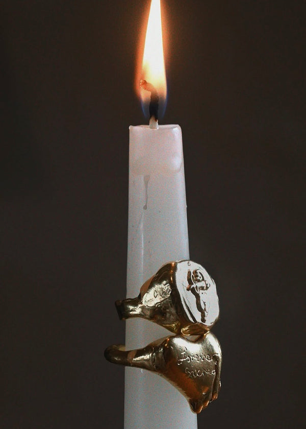 Gold ring on a white candle with a flame against a dark background