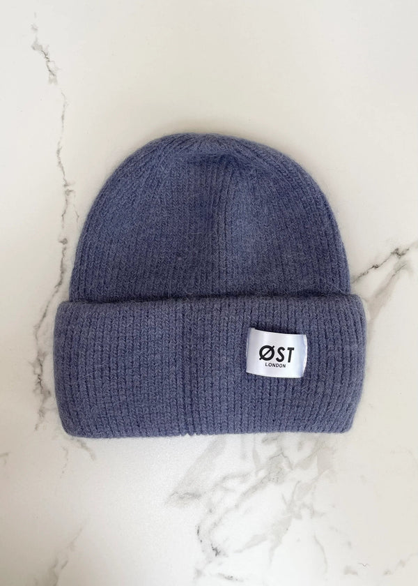 Blue beanie with a white label on a marble surface