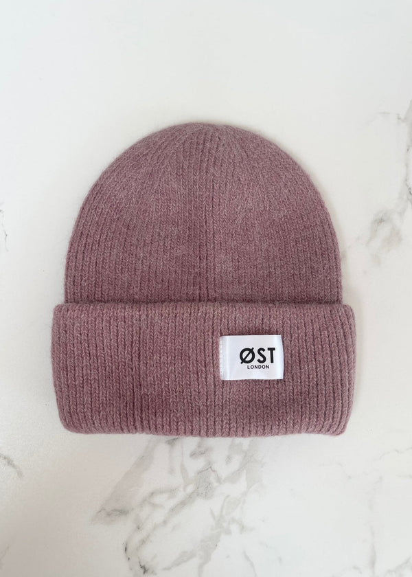 Mauve beanie with a logo on a marble surface