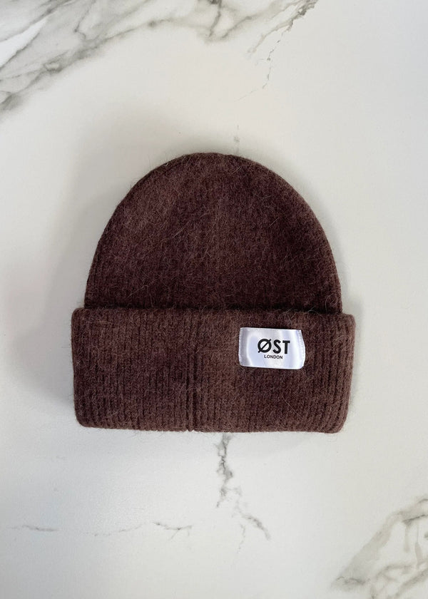 Brown beanie with a logo on a marble surface
