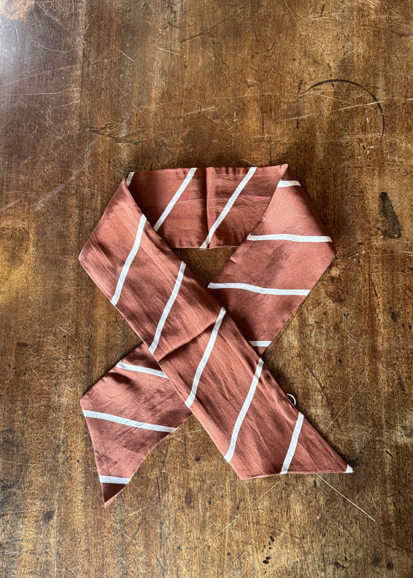 Folded pink fabric with white stripes on a wooden surface