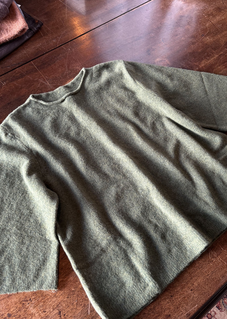 Green sweater on a wooden floor