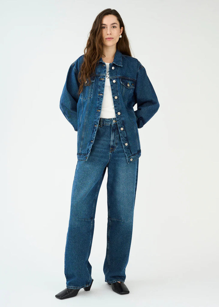 Person wearing a blue denim jacket and jeans on a white background