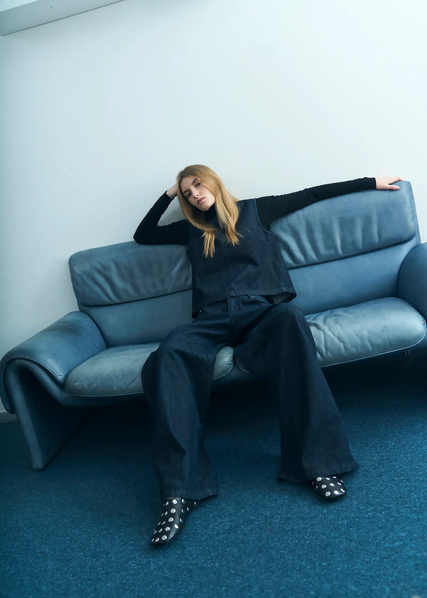 Person sitting on a blue sofa in a minimalistic room