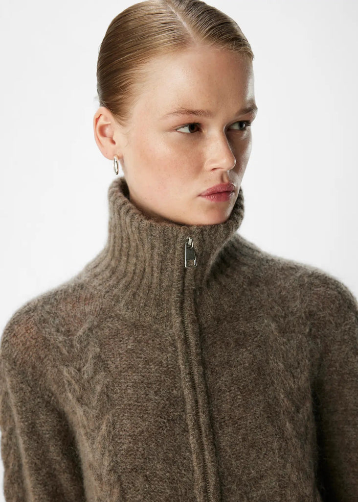 Woman wearing a brown knitted sweater with a zipper on a white background