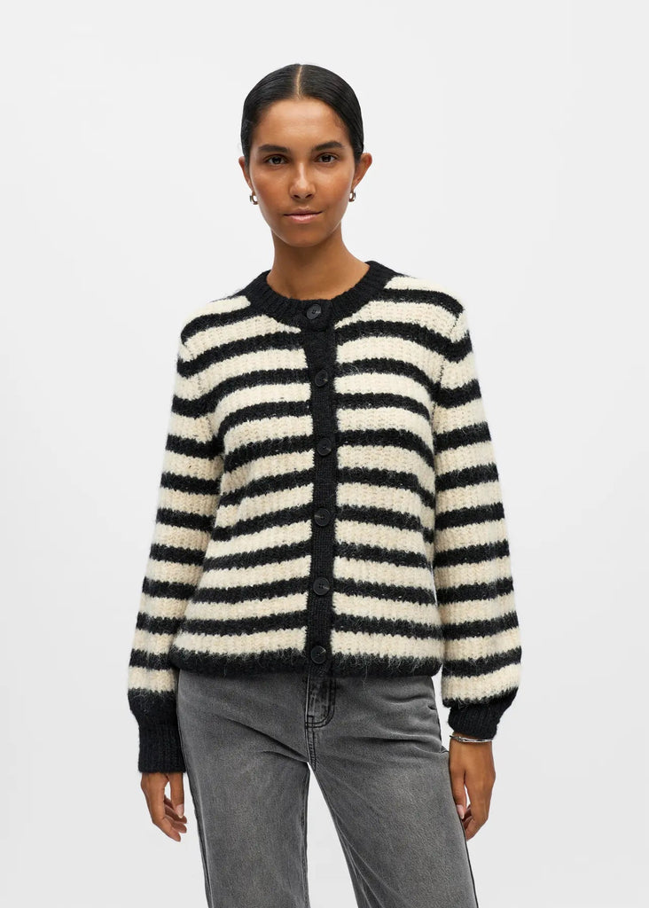 Person wearing a black and white striped cardigan on a plain background