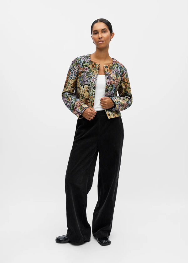 Woman wearing a floral jacket and black pants on a white background