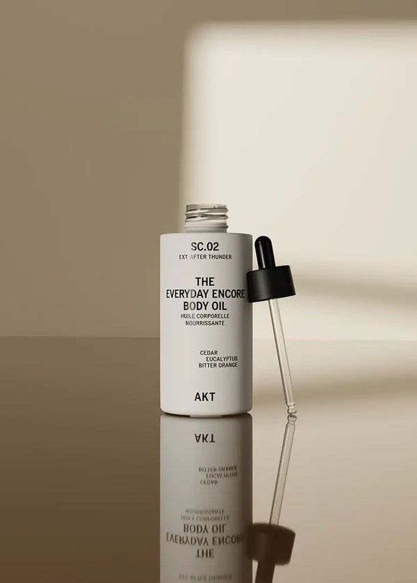 Body oil bottle with dropper on a reflective surface