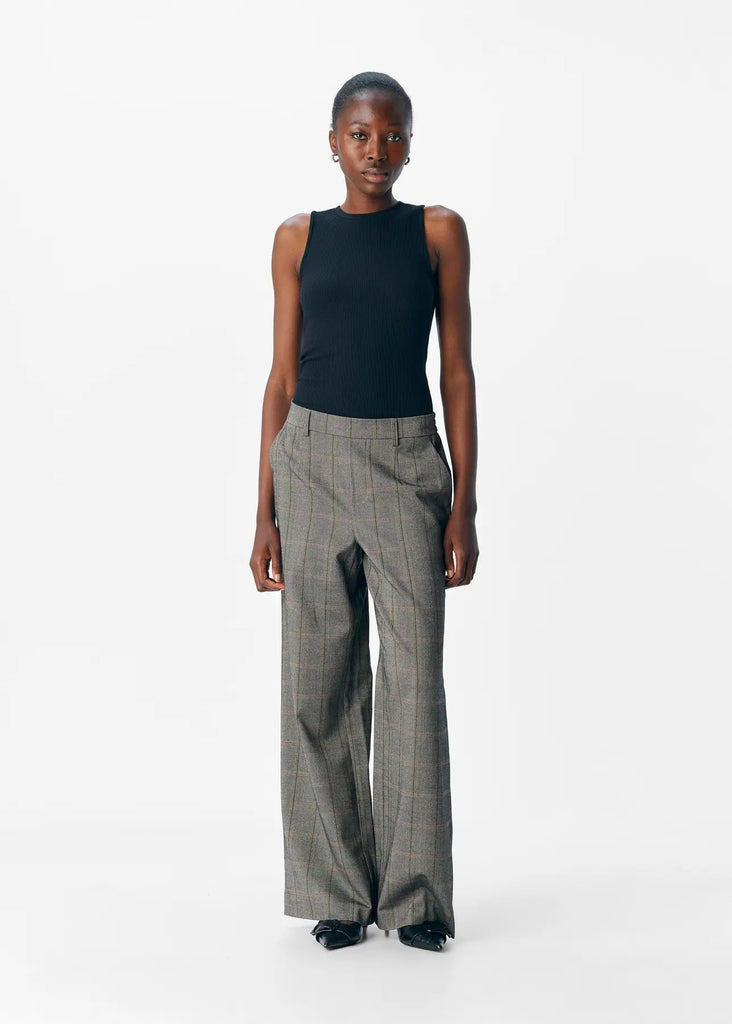 Woman wearing a black sleeveless top and plaid pants on a white background