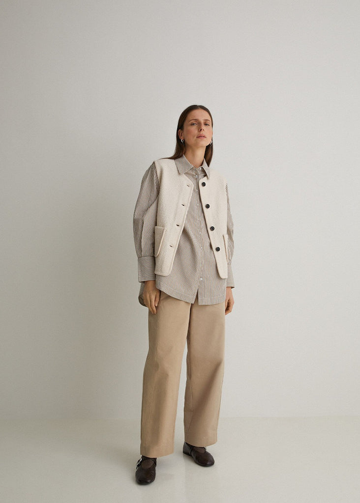 Person wearing a light-colored jacket and beige pants on a white background