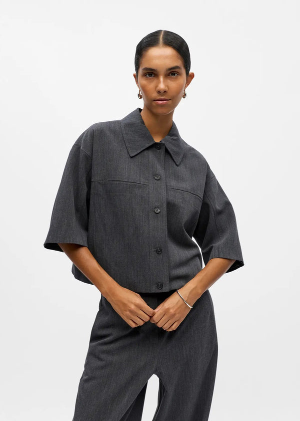 Person wearing a dark gray outfit with a plain background